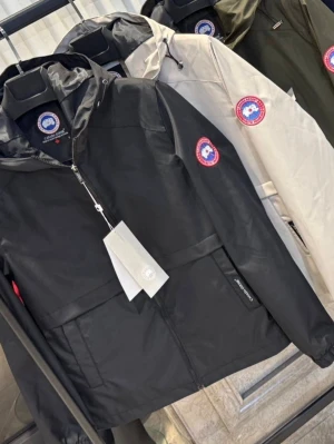 Canada Goose vindjacka med huva - Snygg vindjacka från Canada Goose med huva och dragkedja framtill. Jackan har en klassisk logotyp på ärmen och finns i svart, beige och olivgrön. Tillverkad i ett lätt och slitstarkt material som skyddar mot vind. Perfekt för en stilren och sportig look.