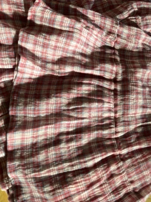 Rutig långkjol i rosa och lila toner - Luftig och flowy långkjol med rutigt mönster i rosa, lila och vita nyanser. Kjolen har smock i midjan och flera volanger som ger en bohemisk känsla. Perfekt för dig som gillar en avslappnad och trendig stil.