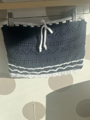 Söt stickad tub topp Hollister - Supersöt mörkblå stickad tub topp från Hollister med vita detaljer.Toppen  har ett mönstrat stickat tyg och vita ränder längst ner och en rosett💕💕