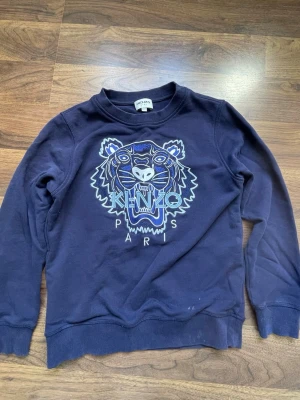 Blå kenzo Paris tröja - Har haft den i ungefär 1 år nu och säljer den för att den är för liten,den har en färg fläck på höger sidan av magen.