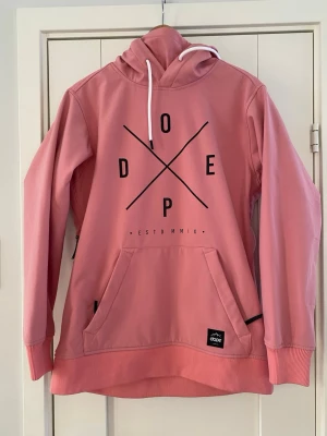 Dope snowboard jacka anorakmodell strl S modell Yeti - Dope jacka för dam i storlek S. Jackan är rosa och tillverkad i polyester. Modellen har huva med dragsko, stor magficka framtill samt tryckt Dope-logotyp på bröstet. Ärmarna har dragkedjeförsedda öppningar i sidorna. Jackan passar som vardagsjacka eller ytterlager vid utomhusaktiviteter.  Det finns en minimal svart liten fläck på baksidan längs ner i övrigt är jackan sparsamt använd och i bra begagnat skick   Mått Över bröstet: ca 59 cm Längd från axeln och ner: ca 70  96% polyester och 4% elast
