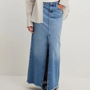 Lång jeanskjol med slits framtill - En snygg lång jeanskjol med slits framtill. Storlek 32, oanvänd med prislappen kvar. Från nakd