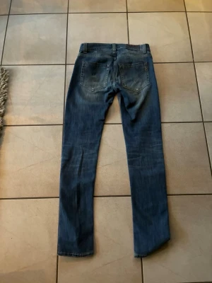 Blå jeans med slitningar - Säljer ett par blå  jeans från dondup med slitningar på låren och knäna. Jeansen har klassisk femficksdesign, normal midja och är tillverkade i denim med stretch för extra komfort. Perfekta för en avslappnad och trendig look. Strorlek ser du på bilden de är bara att höra av sig om de skulle vara nått nyköpta för 1899
