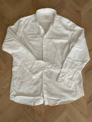 Vit linne skjorta från Massimo Dutti - Klassisk vit skjorta från Massimo Dutti i mjukt tyg. Skjortan har lång ärm, knappar framtill och en tidlös design som passar till många olika stilar. Perfekt för dig som gillar en clean och enkel look.