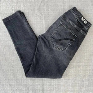 Svarta Dondup Jeans - Säljer ett par svarta jeans från Dondup med smal passform och klassiska fem fickor. Jeansen har en diskret tvättad look och logotypdetalj i midjan. Materialet är mjukt denim med stretch för extra komfort. Kom privat för mer info och ställ frågor om du har några🤙🏽!