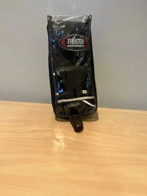 Fighter boxningshandskar svart M - Säljer ett par svarta boxningshandskar från Fighter i storlek M. Hanskarna är 8oz. Handskarna har vita detaljer och är tillverkade i slitstarkt syntetmaterial med vaddering för extra skydd. Perfekta för träning inom boxning eller kampsport.