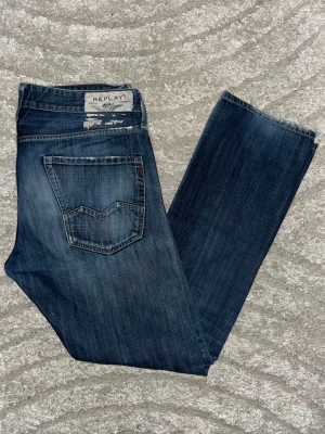 Replay Waitom jeans  - Mörkblåa Replay Waitom Jeans med fade. Obs jeansen har två hål, knät och höger ficka. Midja 48cm, längd 109cm. Bilden är inlånad, för att visa passformen på! Jag har ingen bild när jag bär jeansen på. För bättre inblick i passformen rekommenderar jag att googla på modellnamnet. För storleksguide kolla måtten noggrant då jeansen alltid kan vara uppsydda heller krympta och jag ej tar emot returer :) 1,85