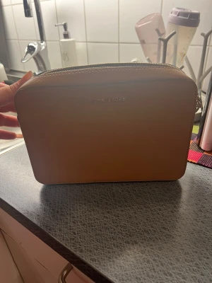 Beige handväska från Michael Kors - Säljer min Michael Kors axelremsväska i äkta slätt läder. Väskan är endast använd två gånger och är i mycket fint skick, som ny och Inga skador, fläckar eller slitage.
