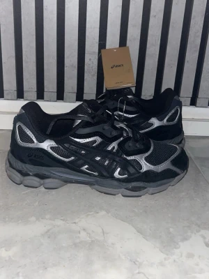 Asics Gel - Snygga svarta ASICS sneakers med silvriga detaljer och meshpaneler för extra ventilation. Skorna har en chunky sula och klassisk snörning. Perfekta för dig som gillar sportig och modern stil. Materialet är en mix av mesh och syntet passar också 41.