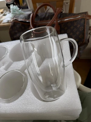 Set med dubbelväggiga glas - Säljer ett set med fyra transparenta dubbelväggiga glas med handtag. Perfekta för både varma och kalla drycker. Glasen har en modern och stilren design och är tillverkade i klart glas. Levereras i skyddande förpackning.