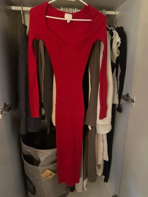 Röd ribbad långklänning H&M - Säljer en röd långklänning från H&M i ribbad bomullsmix. Klänningen har lång ärm, v-ringad hals och figurnära passform som framhäver siluetten. oanvänd 