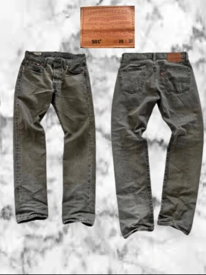 Levis 501 - Säljer ett par gråa jeans från Levi's med klassisk rak passform och fem fickor. Jeansen har en vintage look med diskreta slitningar och Levi's ikoniska läderpatch bak i midjan. Tillverkade i slitstark denim, perfekta för en avslappnad stil. Storlek W28 L32, priset är ej hugget i sten 