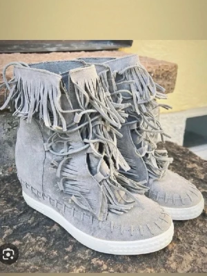 Fina mocka boots liknande casedei skor perfekta till våren och sommaren - Säljer ett par gråa stövletter i mocka med coola fransdetaljer runt hela skon och längs snörningen. Skorna har en vit platåsula och dekorativa sömmar längs kanten. Perfekta för dig som vill sticka ut med din stil.