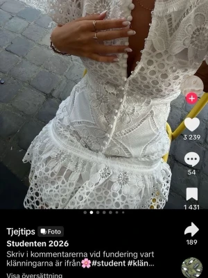 Vit spetsklänning med volang - Superfin vit kortklänning i spets med v-ringning, knappar framtill och volang nertill. Klänningen har korta ärmar och vackra broderade detaljer. Perfekt för student eller en sommar kväll.