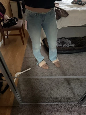 Ljusblå bootcut jeans - Säljer ett par ljusblå bootcut jeans med klassisk femficksdesign och låg midja. Jeansen har en avslappnad passform och är tillverkade i mjuk denim med lite stretch för extra komfort. Perfekta för en casual look och passar till sneakers eller boots.