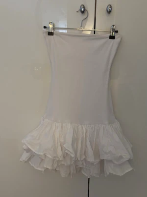 Vit volangklänning från Zara - Supersöt vit kort klänning från Zara med volangkjol. Klänningen har en figurnära passform, kan dock vara lite genomskinlig. Klänningen är storlek M men har en ganska liten passform så skulle säga att den även passar storlek S. Säljer på grund av att den inte används och har endast använts en gång💕
