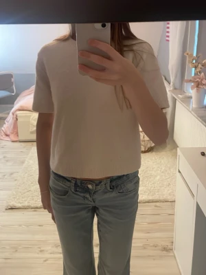 Ljusbeige kortärmad stickad topp - Säljer en ljusbeige stickad topp med korta ärmar och rund hals. Tröjan är lite noppig så kan sänka priset