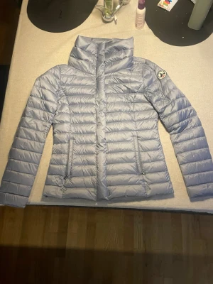 Ljusblå dunjacka från JOTT - Snygg ljusblå  från JOTT med hög krage och två dragkedjeförsedda fickor framtill. Jackan har quiltad design . Perfekt för kalla för alla årstider och riktigt lätt att bära. Den är använd en gång så mycket bra skick Storlek S dam. Priset inte hugget i sten. Kom pm för mer frågor!