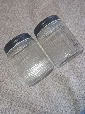 Glasburkar - Säljer två genomskinliga super fina glasburkar med svart skruvlock. Burkarna har ett stilrent räfflat mönster och passar perfekt för förvaring av exempelvis kaffe, te eller småprylar etc. Aldrig kommit till användning