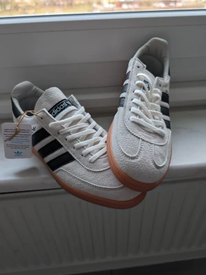Adidas Spezial vita sneakers - Snygga Adidas Spezial sneakers i vitt mocka med klassiska svarta ränder på sidorna. Perfekta för dig som gillar streetwear och tidlös stil.