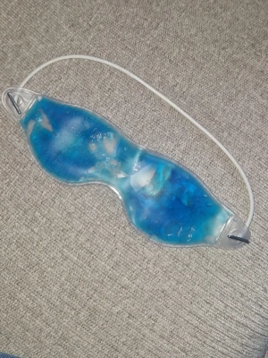 Geleögonmask - Svalkande ögonmask fylld med blå gel, perfekt för avkoppling eller för att minska svullnad runt ögonen. Lägg den bara i kylen eller frysen. Masken har ett vitt elastiskt band som håller den på plats. Passar bra för hemmabruk och self-care stunder.