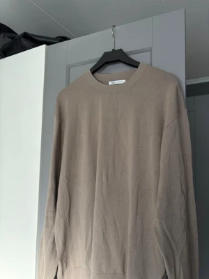 Beige tröja från Zara - Snygg beige tröja från Zara med rund halsringning och långa ärmar. Tillverkad i ett mjukt, tunt material som passar perfekt till lager på lager. Enkel och stilren design som funkar till det mesta.