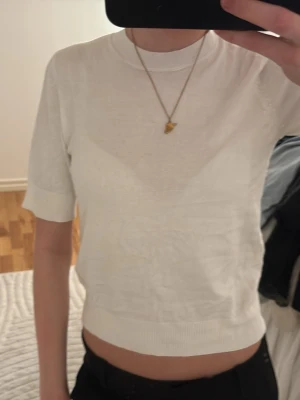 Vit croppad topp med kort ärm -  en enkel och stilren vit croppad topp med korta ärmar och ribbade kanter. Top sopassning är normal och materialet känns som bomull, vilket gör den mj for och skön att bära. Perfekt till jeans eller kjol för en trendig look.