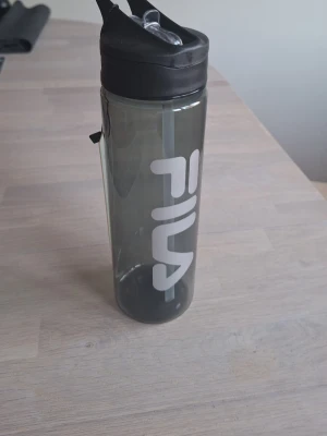 Helt ny vattenflaska från FILA 750 ml - Snygg vattenflaska från FILA i svart plast. Flaskan rymmer 750 ml och är BPA-fri. Praktiskt lock med sugrör gör den enkel att ta med till träning eller vardag.