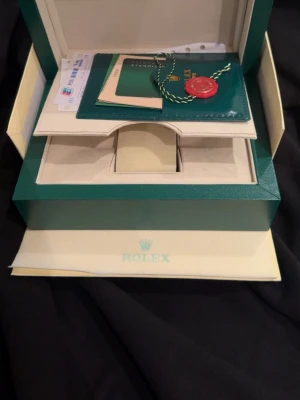  Submariner tvåtonad klocka - Exklusiv  Submariner med svart urtavla och tvåtonad länk i stål och guldfärg. Klockan har klassisk rund form, vridbar bezel och klockan går att justera utan verktyg se bild 5. Klockan har lite små repor här och där. Levereras i originalbox med certifikat och tillbehör (bra kvalitet)