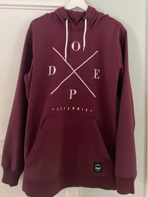 Vinröd hoodie från Dope - Säljer en vinröd hoodie från Dope med vit logga och tryck framtill. Tröjan har huva med vita dragsnören och en stor magficka. Materialet är mjukt och fleecefodrat på insidan, perfekt för kalla dagar. Pris kan diskuteras!! 