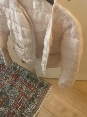 Ljusrosa dunväst från Gina Tricot - Supersnygg ljusrosa tunn dunjackan till våren! Från Gina Tricot med quiltad design och rund hals. Västen har tryckknappar framtill och två fickor. Perfekt att slänga över en hoodie för en chill look. Materialet är mjukt och lätt, vilket gör den enkel att bära.