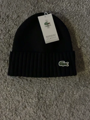 Lacoste Mössa  - Äkta Lacoste mössa, aldrig använd lappen kvar! Skick 10/10 