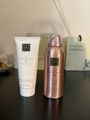 Rituals Sakura body cream & mousse - Säljer två produkter från Rituals The Ritual of Sakura-serien: en vit Magic Touch body cream och en rosa body lotion mousse. Båda har doft av rismjölk och körsbärsblom. Perfekt för dig som vill ha lyxig hudvård med fräsch och blommig känsla.