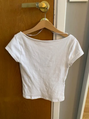 Vit croppad topp med öppen rygg - En vit croppad topp med öppen rygg. Den är ifrån Ginatricot Young i storlek 146/152. Den är inte särskilt mycket andvänd.