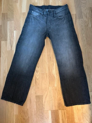 Svarta raka jeans Cheap Monday - Säljer ett par svarta jeans från Cheap Monday med raka ben. Jeansen har en diskret tvättad look och etikett med rosa text i linningen. Perfekta för en avslappnad stil. 