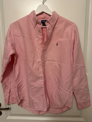 Rosa skjorta från Ralph Lauren - Klassisk rosa skjorta från Ralph Lauren med button-down krage och broderad logga på bröstet. 