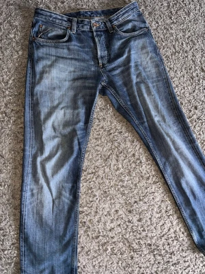 Blå slitna jeans med raka ben. Gant Kyle - Säljer ett par blå jeans med snyggt sliten tvätt och raka ben. Jeansen har klassiska fem fickor och coola detaljer på bakfickorna, inklusive en liten röd söm. Perfekta för en avslappnad streetstil.