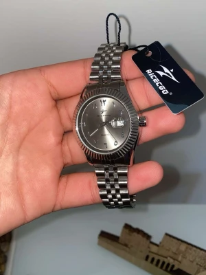 Silverfärgad klocka från Ricego - Stilren klocka från Ricego i helsilver med metallarmband och rund urtavla. Urtavlan har datumvisning och arabiska siffror. Klassisk design som passar till många olika stilar.