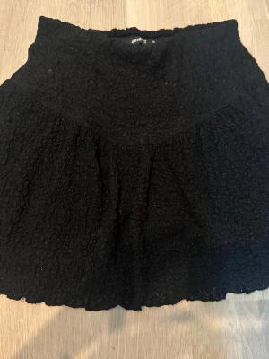 Svart kortkjol från Gina Tricot - Säljer en svart kortkjol från Gina Tricot med struktur i tyget. Kjolen är lågmidjad och lätt utställd passform som ger en skön och avslappnad look. Perfekt att matcha med en enkel topp eller stickad tröja.💕💕
