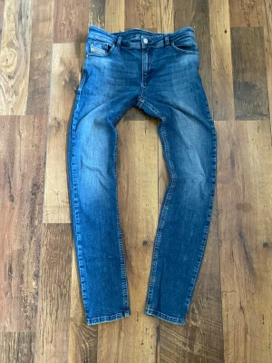 Blå slim fit jeans från Diesel - Snygga blå slim fit jeans från Diesel med klassisk femficksdesign och diskret slitning på framsidan och baksidan. Jeansen har en knappstängning och är tillverkade i denim med stretch för extra komfort.