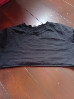Svart basic t-shirt  - En enkel svart t-shirt med rund halsringning och korta ärmar. Perfekt för en clean och stilren look. Passar till allt och är ett måste i garderoben.
