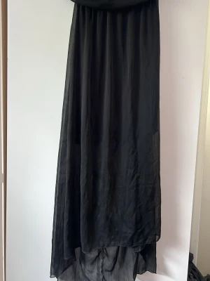 Svart långklänning i luftig polyester - En svart långklänning i luftig och flowy modell med enkel design. Inga axelband 