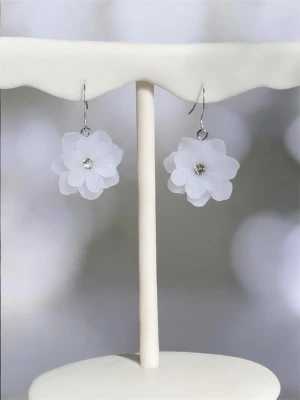 Handgjorda örhängen med vita blommor i polymerlera – Romantiska sommarsmycken (2,2 cm) - Handgjorda blomörhängen i polymerlera med mjuka, transparenta vita toner som fångar ljuset på ett elegant sätt. Varje blomma formas för hand med stor omsorg, vilket gör varje par unikt. Den lilla glittrande kristalldetaljen i mitten ger örhängena ett vackert skimmer. Lätta och bekväma att bära — perfekta till sommaren, för att ge vardagen en extra fin touch. • Handgjorda från grunden • Material: Fimo polymerlera (transparent vit) • Detalj i silverfärg med glittrande kristall • Storlek: ca 2,2 