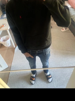 Svart hoodie från Ralph Lauren - Säljer en svart hoodie från Ralph Lauren med den klassiska röda loggan broderad på bröstet. Hoodien har huva och en stor magficka framtill. Perfekt för dig som gillar en enkel men stilren look.