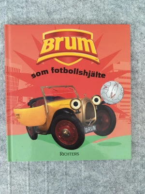 Brum som fotbollshjälte - En färgglad barnbok med Brum, den gula bilen, som huvudperson. Boken har hårda pärmar och illustrationer i starka färger. Brum hjälper till på fotbollsplanen och boken är fylld med roliga bilder och lättläst text.