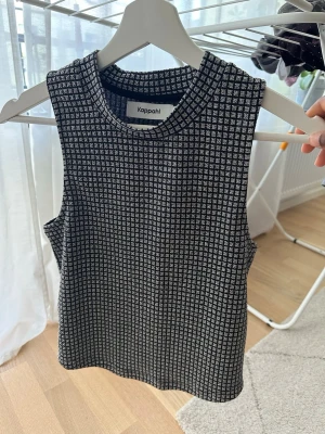 Svart/glittrig rutig linnetopp Kappahl - Snygg svart glittrig linnetopp från Kappahl med rutigt mönster. Perfekt att styla med jeans eller kjol för en trendig look.