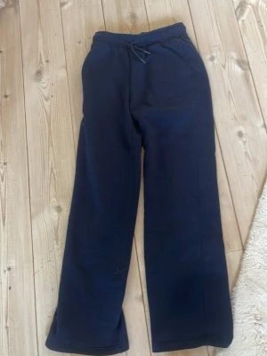Mörkblå mjukisbyxor från Primark - Mörkblå mjukisbyxor från Primark med dragsko i midjan och raka ben. Tillverkade i mjukt och bekvämt material som passar perfekt för chill dagar. Klassisk modell utan synliga loggor eller detaljer.