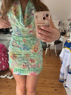 Ibiza dress - Klänning med blommigt mönster och paljetter. Glittrig och figursydd med en hängande uringad topp, storlek xs