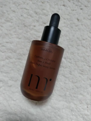 Molvany Pore Tightening Serum 50ml - Säljer ett Molvany Castanea Crenata Inner Shell Pore Tightening Serum i brun glasflaska med svart pipett. Flaskan rymmer 50 ml och har en stilren design. Perfekt för dig som vill ha ett serum som hjälper till att minska porer.