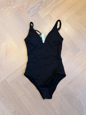 Svart baddräkt med v-ringning - Otroligt classy och stilren baddräkt , skulle säga A-B (C) kupa. Den är vadderad och har som en bygel där fram så att den håller sin form bra! Aldrig använd, skulle säga att den passar bäst om man är mellan S och XS i storlek 